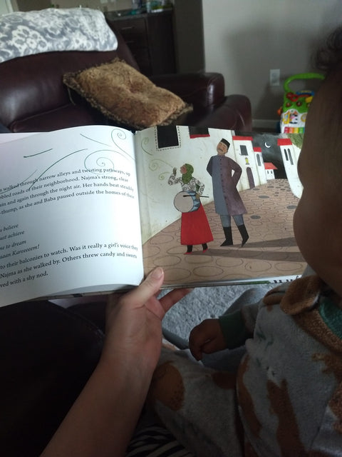 mother showing images from Drummer Girl book to her baby